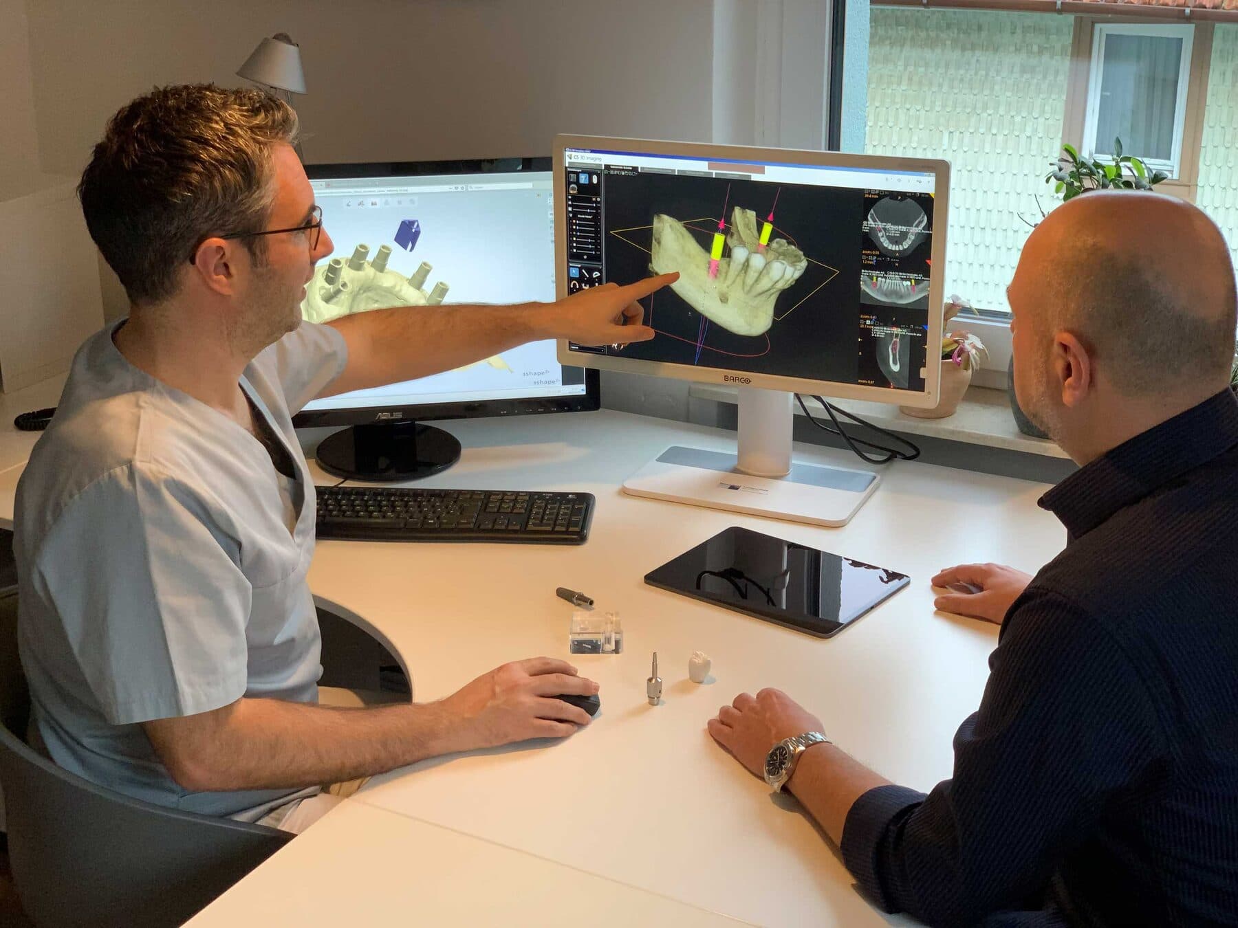 Zahnarzt erklärt einem Patienten die 3D-Planung am Bildschirm